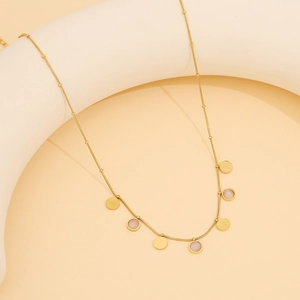 Détail macro de la chaîne dorée avec pendentifs en pierres roses et perles rondes dorées