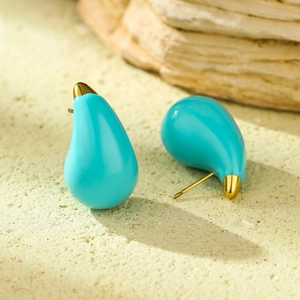Macro shot of sky blue waterdrop earrings with gold tips and glossy ceramic texture