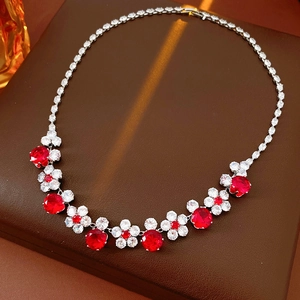 Detail of flower necklace featuring red zircon stones and shimmering crystal accents