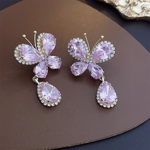 Gros plan de boucles d'oreilles papillon en argent avec cristaux roses et pavé de diamants