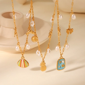 Detail of gold ocean-themed necklace with shell pendants, pearls and colorful enamel charms
