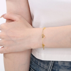 Gold minimalist stainless steel heart bracelet on model's wrist with casual outfit