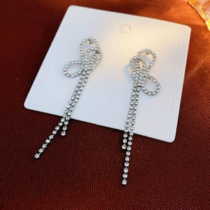 Macro shot of silver bow knot earrings with long sparkling rhinestone fringe tassels