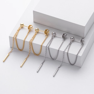Detail view of long tassel chain earrings in gold and silver finish on white blocks