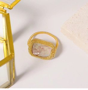 Close-up of golden spring band ring featuring a pearlescent shell inlay and woven metal detail