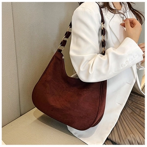 Detail of dark brown suede shoulder bag featuring a unique gold chain and leather strap