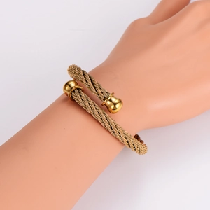 Detail of gold twisted wire cuff bracelet featuring sphere ends on a model wrist
