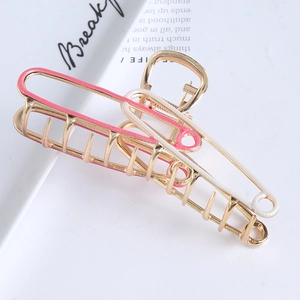 Geometric hollow metal hair claw clip in pink and white drip oil finish on a plate