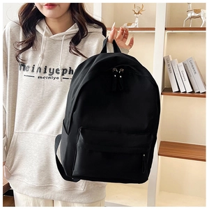 Close-up of minimalist black large capacity backpack with top handle and front pocket