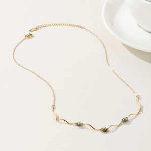 Golden wavy beaded necklace with turquoise and brown accents on minimalist white background