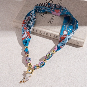 Detailed shot of ethnic silk scarf necklace with ivory pendant and evil eye charm