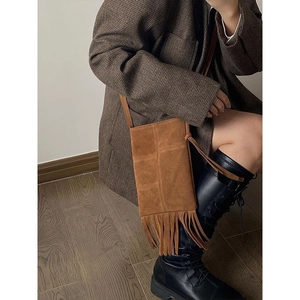 Detail shot of brown bohemian crossbody bag featuring elegant suede tassels and fine stitching