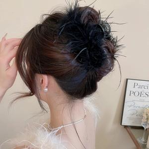 Detail of the black feather hair claw clip on model with elegant pearl jewelry accents