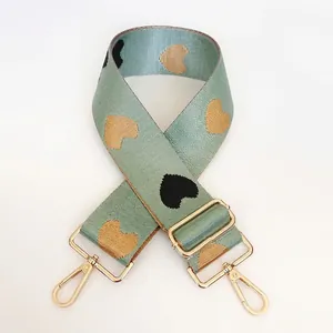 Detail of mint green nylon bag strap with heart jacquard pattern and gold metal hooks