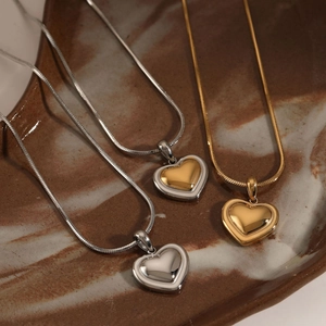Polished heart pendant necklaces in gold and silver finish on a ceramic plate