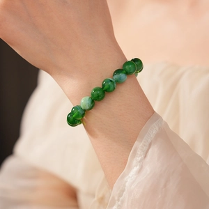 Close-up of elegant 10mm green gemstone beaded bracelet on woman's wrist
