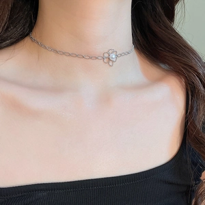 Close-up of a silver hollow flower pendant necklace with elegant pearl details on a model