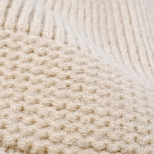 Macrodetail van een dikke crème gebreide muts met een zachte wollen textuur voor de