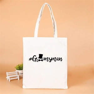 Detail of white canvas tote bag with black Groomsman text and bow tie hat icons