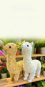 Close-up of fluffy white and brown alpaca plush toys in a scenic garden setting