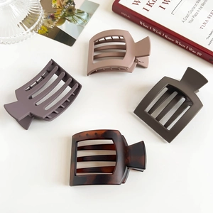 Detail of four large square hair claws in matte colors and tortoiseshell pattern on white