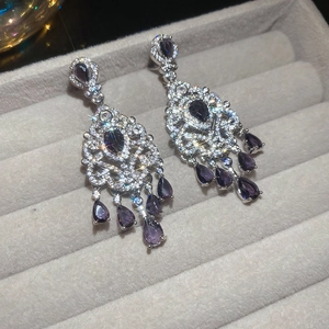Close-up of vintage silver earrings with purple zircon tassels in a grey jewelry box