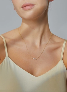Close-up of elegant gold cross necklace with pavé zircons on a female model