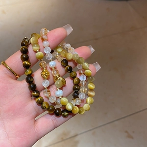 Gros plan du bracelet en œil de tigre et perles avec pendentif lotus doré élégant