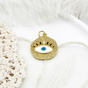 Detailed macro view of a gold evil eye charm with blue enamel on white lace background