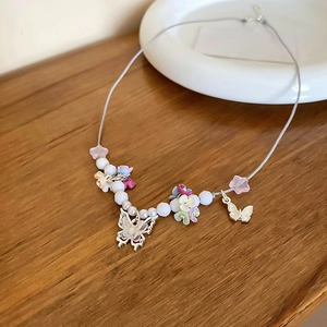 Detailed macro shot of butterfly charms and colorful resin flower beads on the necklace
