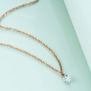 Close-up of rose gold cross chain with a round cut clear crystal solitaire pendant