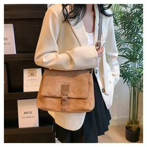 Detail of a brown suede shoulder bag featuring a metallic buckle and soft matte texture