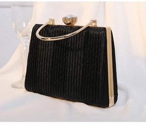 Detail of black pleated evening bag with golden handle and large crystal clasp