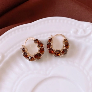 Vintage gold-plated hoop earrings with amber crystals on a decorative white porcelain plate