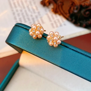 Gros plan de boucles d'oreilles fleur en perles roses et diamants sur boîte verte
