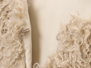 Detailed macro view of invisible hook closure on beige faux fur vest texture