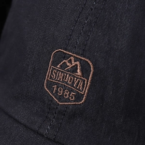 Detailed close-up of embroidered shield badge with SMUOYA logo on navy cotton baseball cap