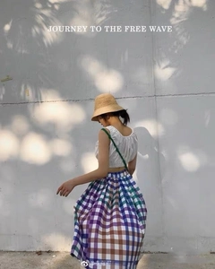 Close-up of a handmade raffia sun hat paired with a white top and checkered maxi skirt