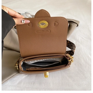 Détail de l'intérieur du sac avec serrure dorée et large bandoulière géométrique