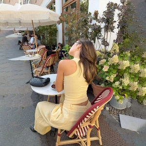 Outdoor shot of a woman in a pale yellow ribbed tank top and linen wide-leg pants