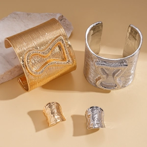 Gold and silver metal cuffs with bow relief and matching geometric rings set