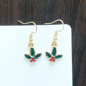 Detailed close-up of Christmas holly leaf earrings with red berries on white card