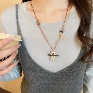 Cute ceramic cat pendant necklace with wooden beads and brown woven rope on a model