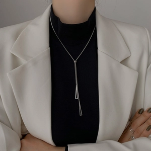 Minimalist silver triangle pendant long chain necklace worn on black turtleneck sweater