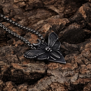 Retro biker style stainless steel necklace featuring a moth and skull pendant on tree bark