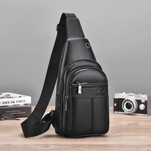 Detail view of black textured leather men's chest bag with metal headphone port