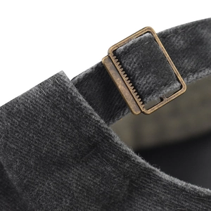 Macro detail of dark grey corduroy cap with vintage brass buckle and adjustable strap