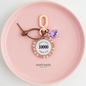 Detail of handmade poker chip keychain with purple dice and silicone beads on pink tray