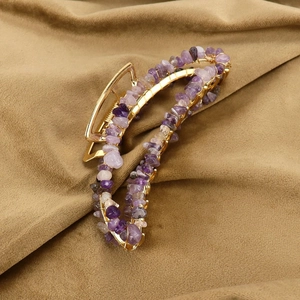 Detailed macro view of purple natural crystal stones on a golden metal banana hair clip