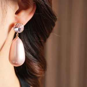 Gros plan de boucles d'oreilles perles roses en goutte avec diamants portées par un mannequin